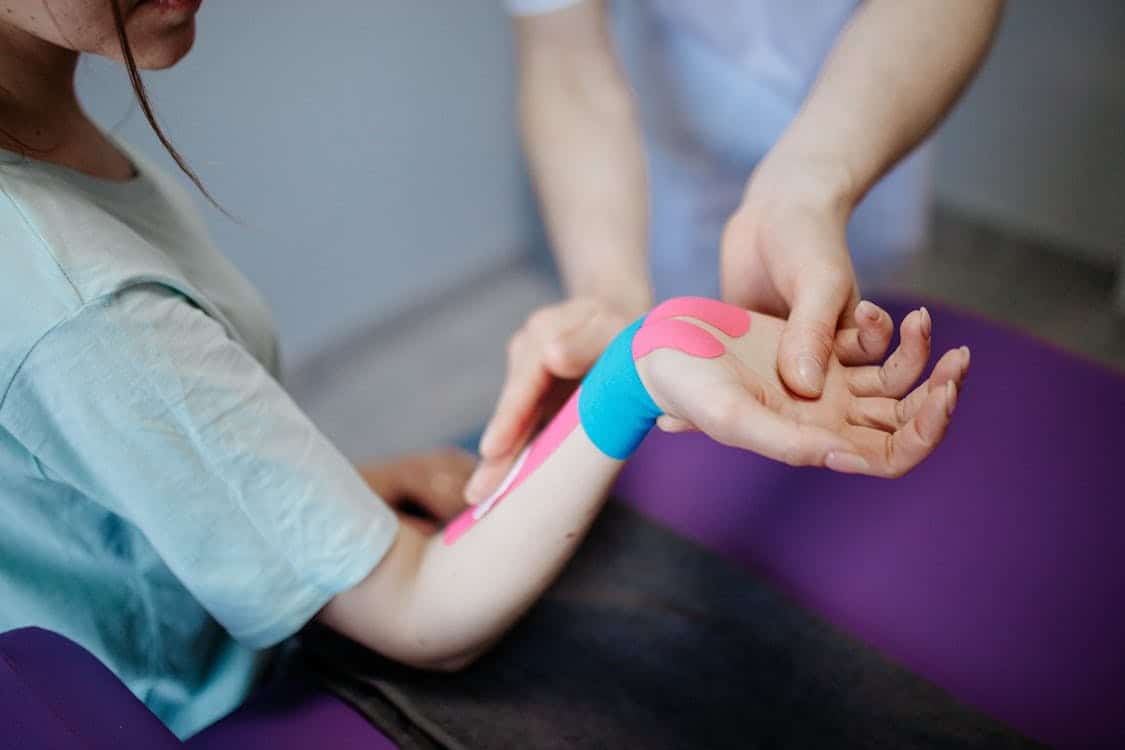 Physical therapist applying kinesio tape to ankle for pain relief and support