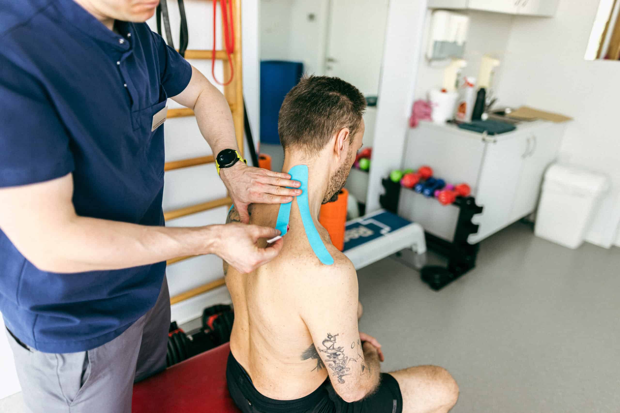 Physical therapist applying kinesiology tape to patient's neck at Trinity Rehab